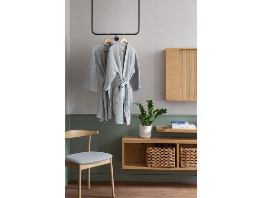 hotel bedroom with two grey dressing gowns hanging up