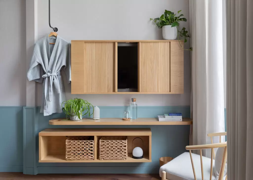 hotel bedroom seating area with hanging robe and tv