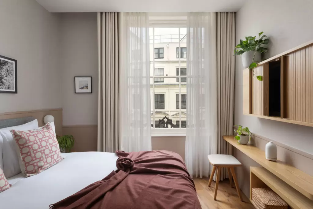 inhabit hotel bedroom with burgundy blanket