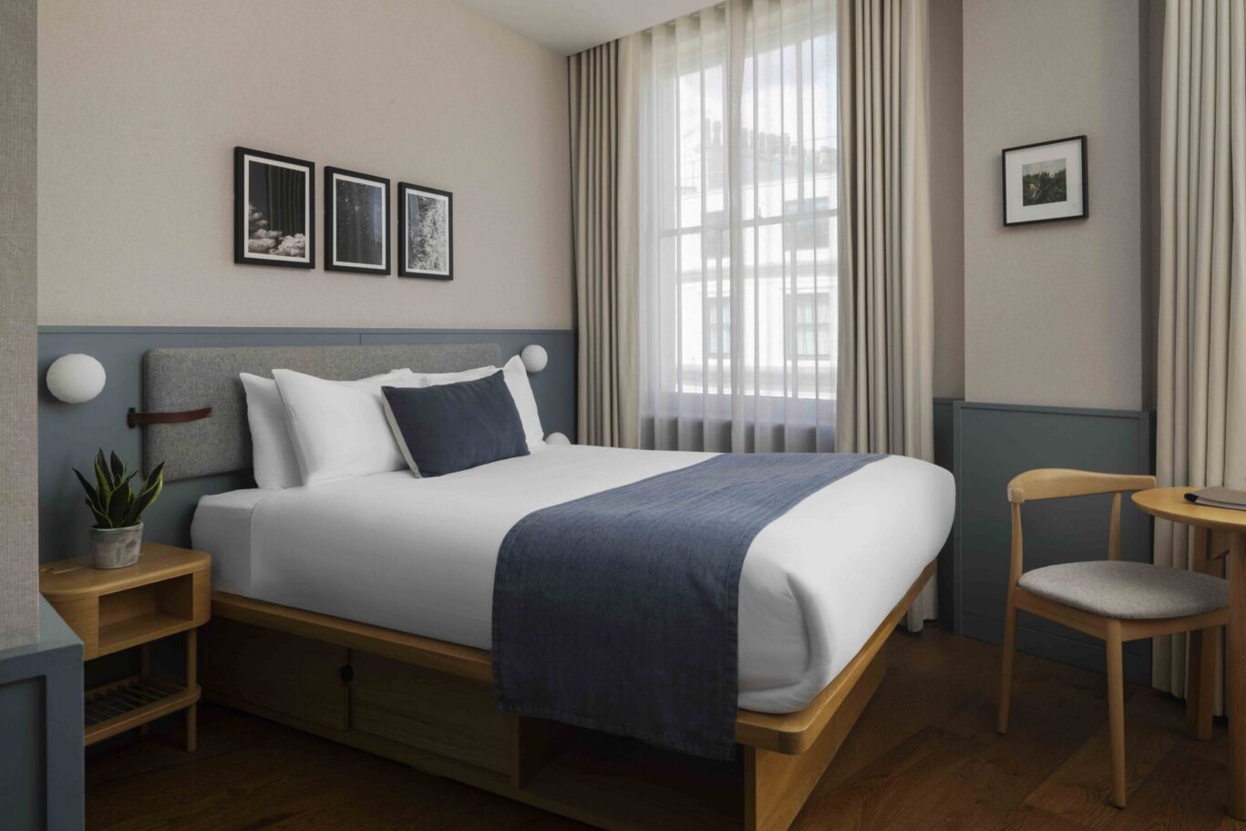Roomy hotel room with large window at Inhabit Queen's Gardens